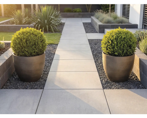 Moderner Gartenweg aus hellen Steinplatten, flankiert von zwei großen, geriffelten Pflanzgefäßen mit kugelförmig geschnittenen Buchsbäumen.