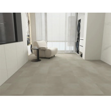 Großformatige Bodenfliesen in hellem Grau, moderner Wohnbereich mit weißem Sessel, Beistelltisch und Fensterfront, heller und geräumiger Raum.