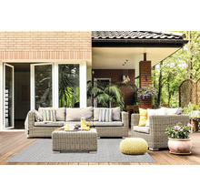 Hell gestaltete Terrasse mit Polyrattan-Sitzgruppe, gemustertem Outdoorteppich, gelbem Strick-Pouf und Pflanzen auf einem Holzdeck.