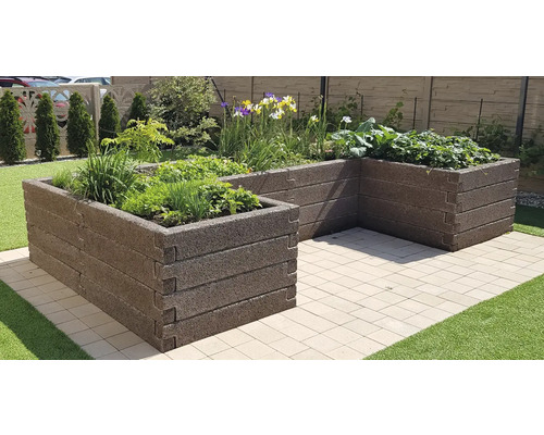 U-förmiges Hochbeet aus dunkelbraunen, strukturierten Modulen auf einer gepflasterten Terrasse, bepflanzt mit Kräutern, Gemüse und Blumen.