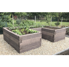 U-förmiges Hochbeet aus ineinandergreifenden Steinelementen, bepflanzt, auf hellem Kies im Garten.