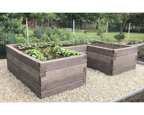 U-förmiges Hochbeet aus ineinandergreifenden Steinelementen, bepflanzt, auf hellem Kies im Garten.