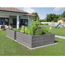 Zwei dunkelgraue Hochbeete aus strukturierten Modulen in einem hellen Garten mit Rasen, Wohnhaus und Spielplatz im Hintergrund.