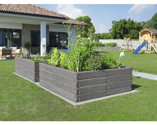 Zwei dunkelgraue Hochbeete aus strukturierten Modulen in einem hellen Garten mit Rasen, Wohnhaus und Spielplatz im Hintergrund.