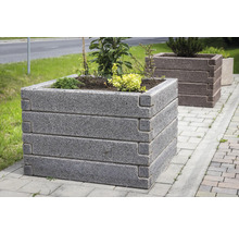 Quadratisches Hochbeet aus Steinblöcken mit Eckverzahnung, bepflanzt im Außenbereich auf Pflastersteinen.