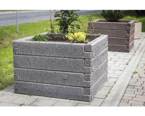 Quadratisches Hochbeet aus Steinblöcken mit Eckverzahnung, bepflanzt im Außenbereich auf Pflastersteinen.