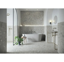 Modernes Badezimmer mit grauen Terrazzo-Fliesen, freistehender Badewanne, Rundbogen-Dusche und minimalistischem Waschtisch.