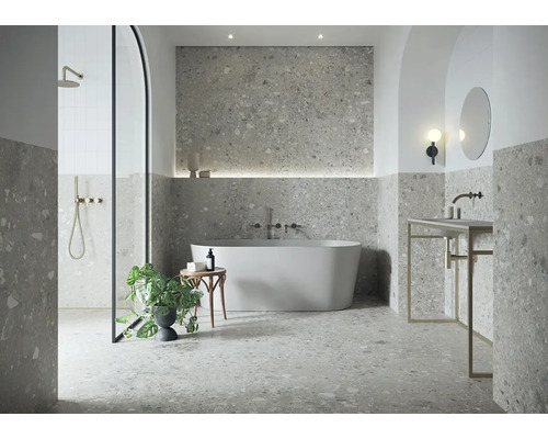 Modernes Badezimmer mit grauen Terrazzo-Fliesen, freistehender Badewanne, Rundbogen-Dusche und minimalistischem Waschtisch.