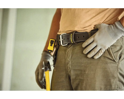 Lederner Arbeitsgürtel mit Stanley Logo an einer Person in Arbeitskleidung mit Arbeitshandschuhen und Werkzeug.