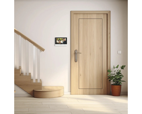 Moderne Diele mit Video-Türsprechanlage an der Wand neben einer hellen Holztür und einer Treppe.