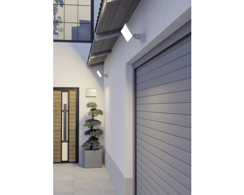Zwei flache LED-Außenstrahler an einer weißen Hauswand beleuchten den Garagen- und Eingangsbereich eines modernen Wohnhauses.