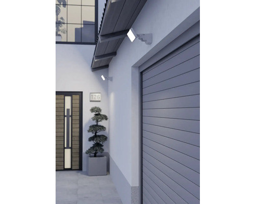 Moderne LED-Außenstrahler an einer hellen Hauswand über einem Garagentor und neben einer Haustür.