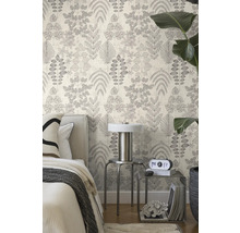 Vliestapete mit botanischem Blattmuster in einem hellen Schlafzimmer mit Bett, Metalltischen und einer großen Zimmerpflanze.