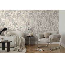 Tapete mit botanischem Blattmuster in einem modern eingerichteten Wohnzimmer mit Sofa, Sessel und Parkettboden.