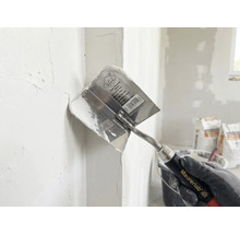 Maurerlob Inneneckspachtel beim Verteilen von Spachtelmasse in einer Wandecke.