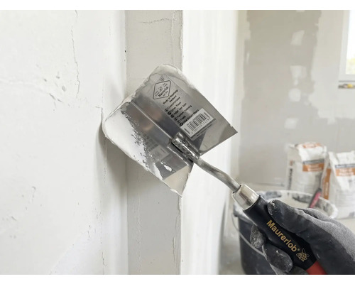 Maurerlob Inneneckspachtel beim Verteilen von Spachtelmasse in einer Wandecke.