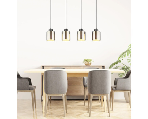 Vierflammige Pendelleuchte mit geriffelten Glasschirmen über Holztisch mit grauen Polsterstühlen in hellem, modernem Esszimmer.