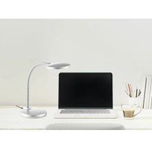 Silberne LED Schreibtischleuchte mit flexiblem Arm neben einem Laptop auf einem hellen Schreibtisch.