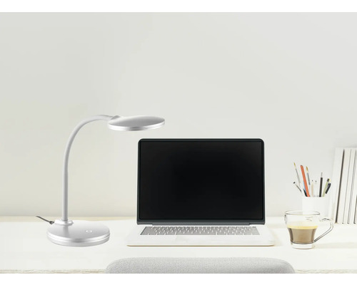 Silberne LED Schreibtischleuchte mit flexiblem Arm neben einem Laptop auf einem hellen Schreibtisch.