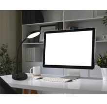 Moderne LED-Schreibtischleuchte auf einem organisierten Schreibtisch mit Monitor, Tastatur und weißem Becher in einem hellen Arbeitszimmer.