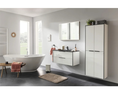 Modernes Badezimmer mit freistehender Badewanne, wandhängendem Waschtischunterschrank und hohem Badschrank in Weiß mit schwarzen Akzenten.