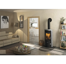 Moderner schwarzer Kaminofen mit Steinverkleidung und brennendem Feuer in einem hellen Wohnzimmer mit Glasbodenplatte.