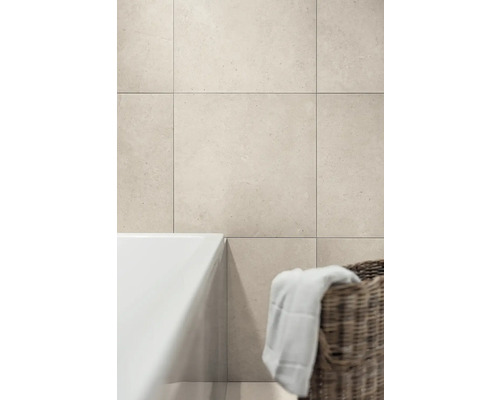 Wandfliesen in Natursteinoptik in einem Badezimmer mit Badewanne und Weidenkorb.