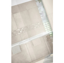 Helles Badezimmer mit großformatigen Wandfliesen in Steinoptik und einer horizontalen Mosaikbordüre über einer weißen Badewanne.