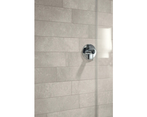 Moderne Einhebel-Duscharmatur in Chrom auf einer Wand mit großformatigen, hellgrauen Fliesen in Natursteinoptik.
