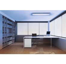 Moderner heller Büroraum mit weißem Schreibtisch, schwarzem Bürostuhl, deckenhohem Bücherregal, Holzboden und Fenstern mit vertikalen Lamellen.