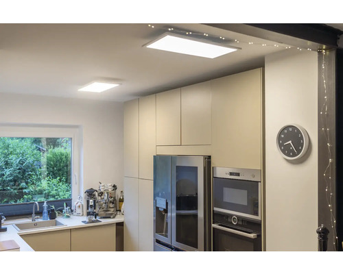 Moderne helle Küche mit zwei flachen rechteckigen LED-Deckenpaneelen, Einbauschränken und Edelstahlgeräten.