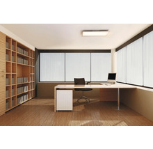 Modernes Arbeitszimmer mit hellem Schreibtisch, schwarzem Bürostuhl, großem Wandregal aus Holz und bodentiefen Fenstern mit Lamellen.