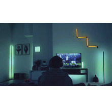 Modernes Wohnzimmer mit verschiedenen LED-Stehlampen und einer LED-Wandleuchte für indirekte Smart Home Beleuchtung beim Fernsehen.