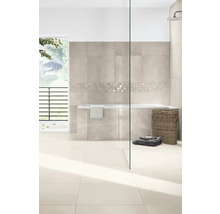 Modernes, helles Badezimmer mit beigen Wand- und Bodenfliesen, Mosaikbordüre, Einbaubadewanne, Glasduschwand und Weidenkorb.