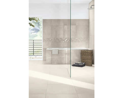 Modernes, helles Badezimmer mit beigen Wand- und Bodenfliesen, Mosaikbordüre, Einbaubadewanne, Glasduschwand und Weidenkorb.