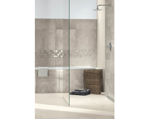 Modernes Badezimmer mit großformatigen Wandfliesen in Steinoptik, einer Mosaikbordüre, Badewanne, Glasduschwand und Regendusche.