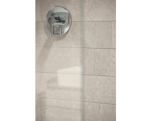 Moderne Einhebel-Mischbatterie in Chrom auf hellen Wandfliesen in Steinoptik.