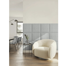 Modernes, helles Wohnzimmer mit quadratischen, gepolsterten Wandpaneelen aus hellblauem Stoff neben einem runden Sessel aus weißem Bouclé-Stoff.