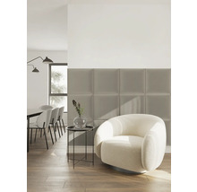 Quadratische Polsterpaneele an der Wand in einem modernen Wohnzimmer mit Bouclé Sessel und Beistelltisch auf Holzboden.