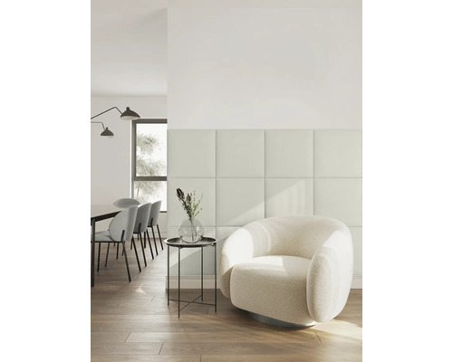 Modernes, helles Wohnzimmer mit quadratischen Wandpaneelen, einem runden Sessel aus Bouclé und einem Essbereich im Hintergrund.