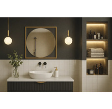 Modernes Badezimmer mit dunklem Waschtisch, weißem Aufsatzbecken, schwarzer Armatur, rundem Spiegel im Goldrahmen und beleuchteter Wandnische.