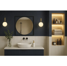 Modernes Badezimmer mit weißem Aufsatzwaschbecken, dunkelblauem Unterschrank, rundem Spiegel und beleuchteter Wandnische.