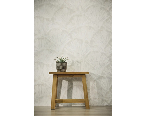 Tapete mit fächerförmigem Blättermuster, kleiner Holzschemel mit Sukkulente im Topf vor einer hellen Wand.