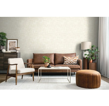 Modernes Wohnzimmer mit strukturierter cremefarbener Tapete, braunem Ledersofa, weißem Sessel und rundem Leder-Pouf.