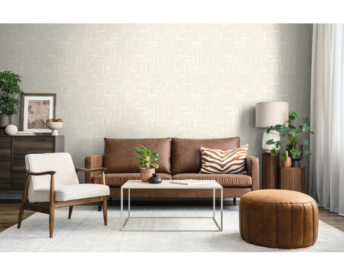 Modernes Wohnzimmer mit strukturierter cremefarbener Tapete, braunem Ledersofa, weißem Sessel und rundem Leder-Pouf.