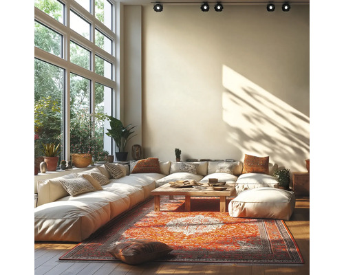 Helles Wohnzimmer mit großem modularem Sofa, Holztisch und Orientteppich vor einer großen Fensterfront mit Deckenstrahlern.