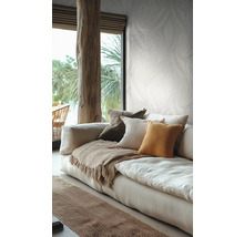 Helles Wohnzimmer mit botanisch gemusterter Tapete, einem Leinensofa mit Kissen und einem rustikalen Holzbalken.