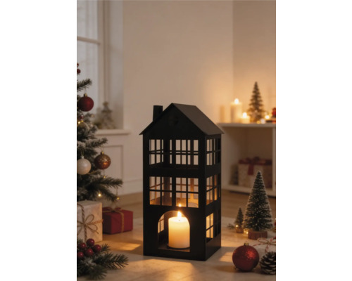 Schwarze Metall-Laterne in Hausform mit brennender Kerze in einer weihnachtlichen Szene mit geschmücktem Tannenbaum und Geschenken.