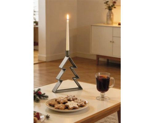 Gerippter Metall-Kerzenständer in Tannenbaumform mit brennender weißer Stabkerze auf einem Tisch neben Keksen und einem Glas Heißgetränk.
