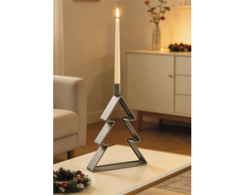 Kerzenständer aus Metall in Weihnachtsbaumform mit brennender Stabkerze auf einem Tisch in einem festlich dekorierten Wohnzimmer.